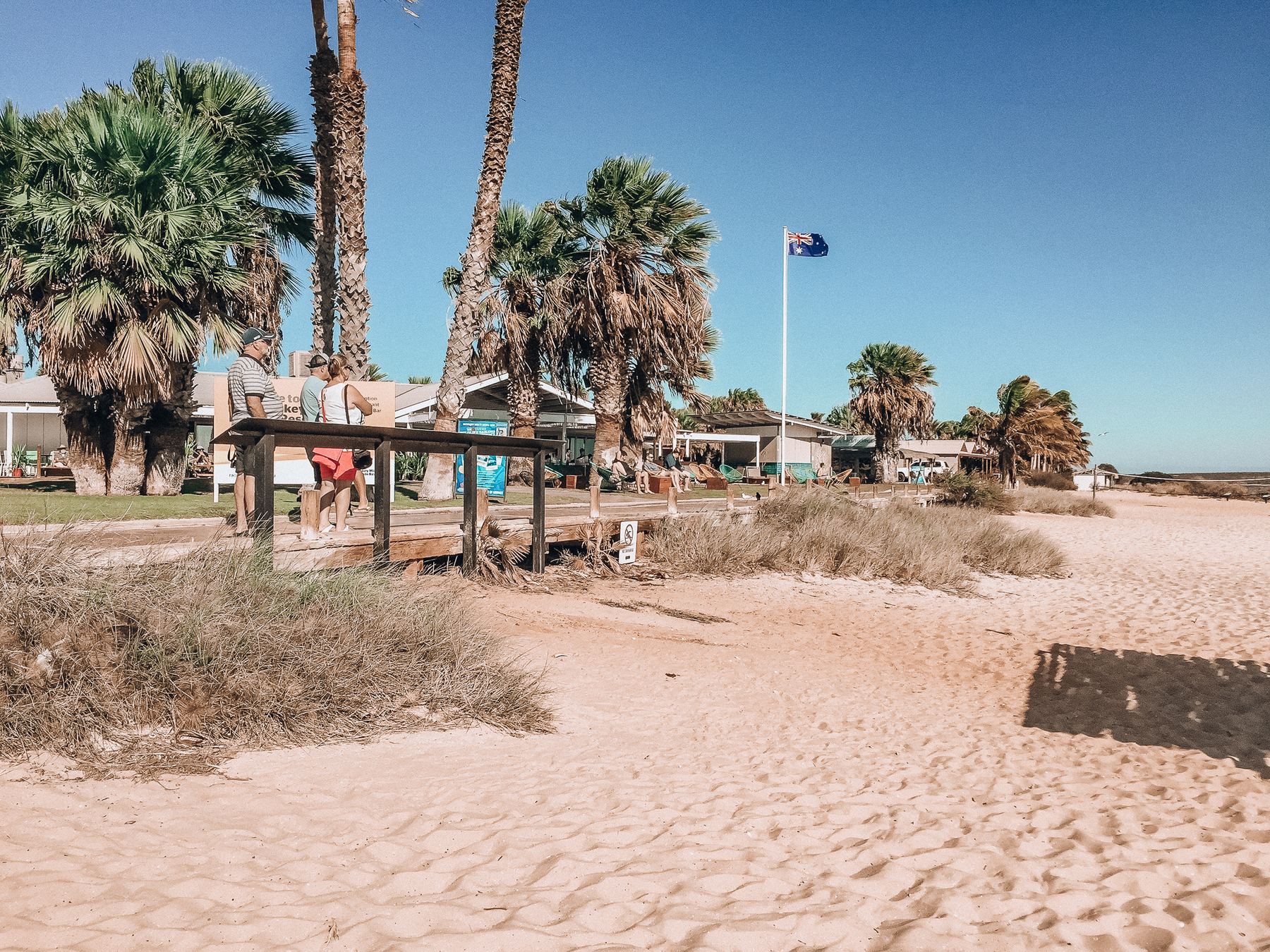 Von Palmen beschatteter Strandbereich mit Picknickhütten und australischer Flagge